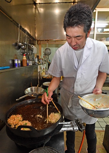 ひまわり油にたねを落とし、菜箸で穴を開けながらかき揚げを仕上げていく＝５月下旬、静岡市清水区の井筒屋